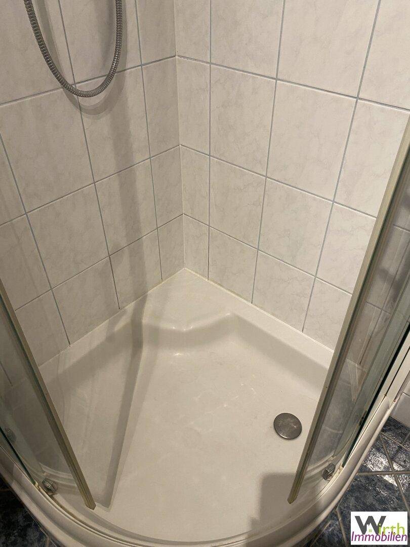 Eckduschkabine mit weißen Fliesen und blauen Akzenten im Badezimmer.