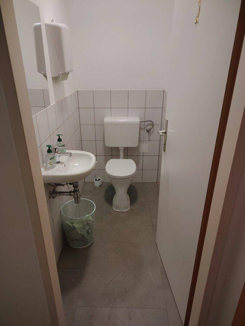 Funktionale Toilette mit Waschbecken und WC, ausgestattet mit Fliesen an Wänden und Boden.