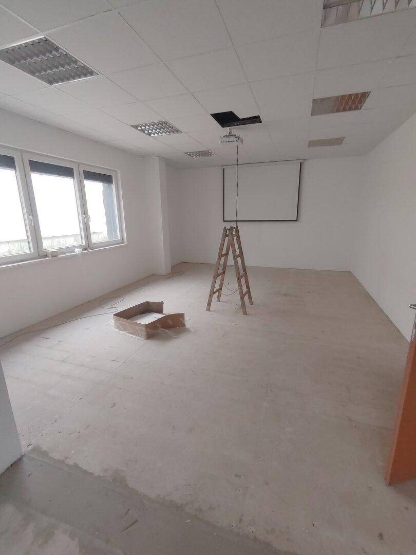 Konferenzraum in Renovierung mit Projektionsleinwand und Leiter, bereit für neue Bodenbeläge.
