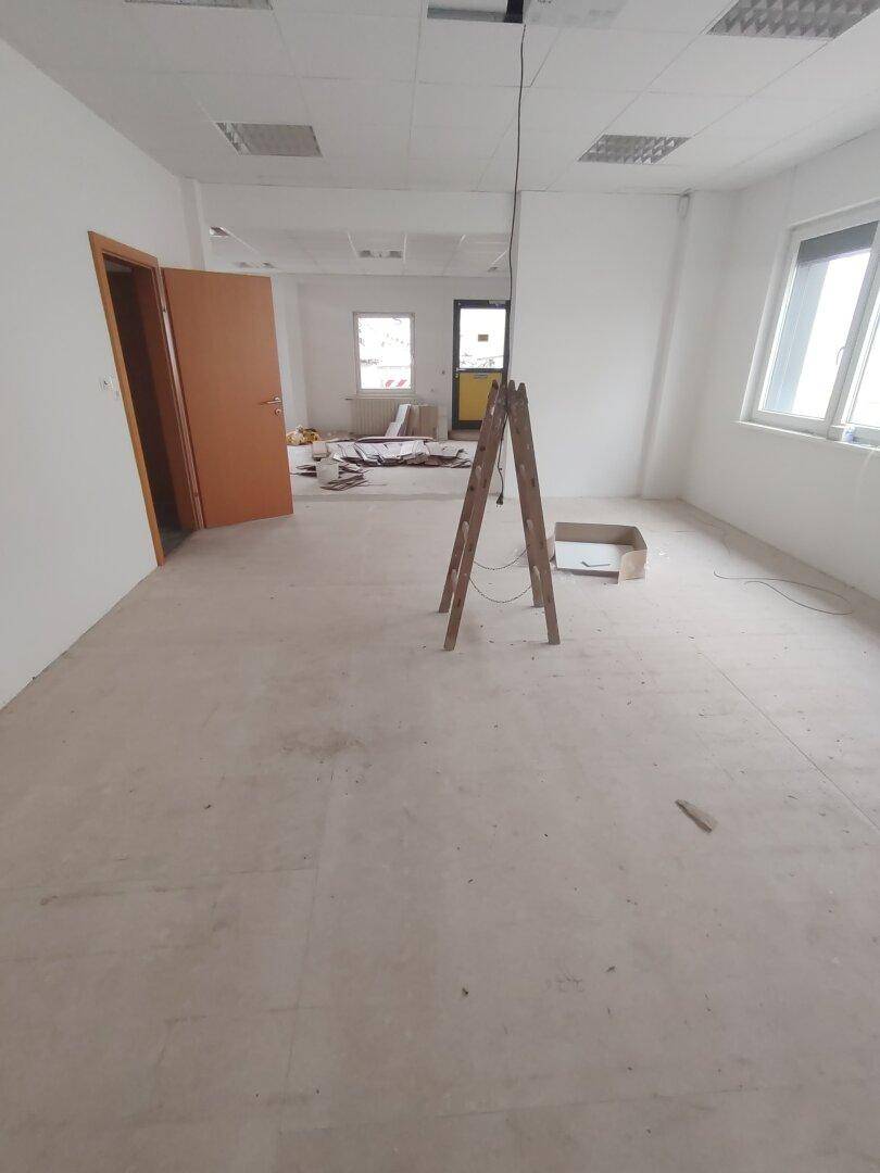 Großer Raum in Renovierung mit mehreren Türen und Fenstern, der auf Fertigstellung wartet.