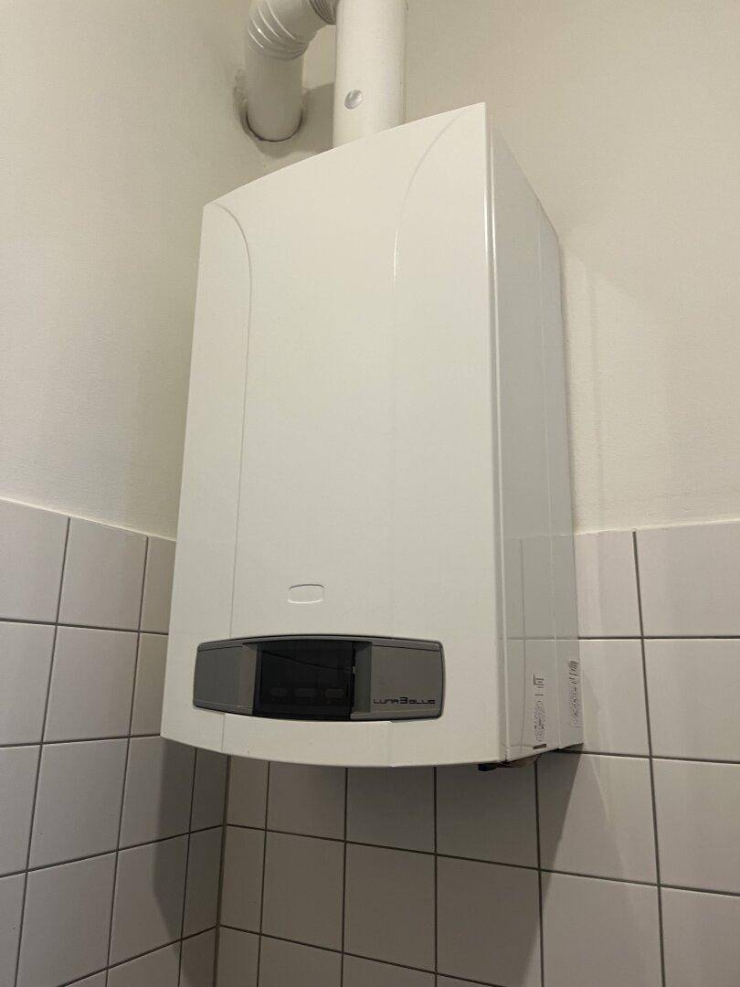 Nahaufnahme einer modernen Gastherme an einer gefliesten Wand, für Warmwasser und Heizung.