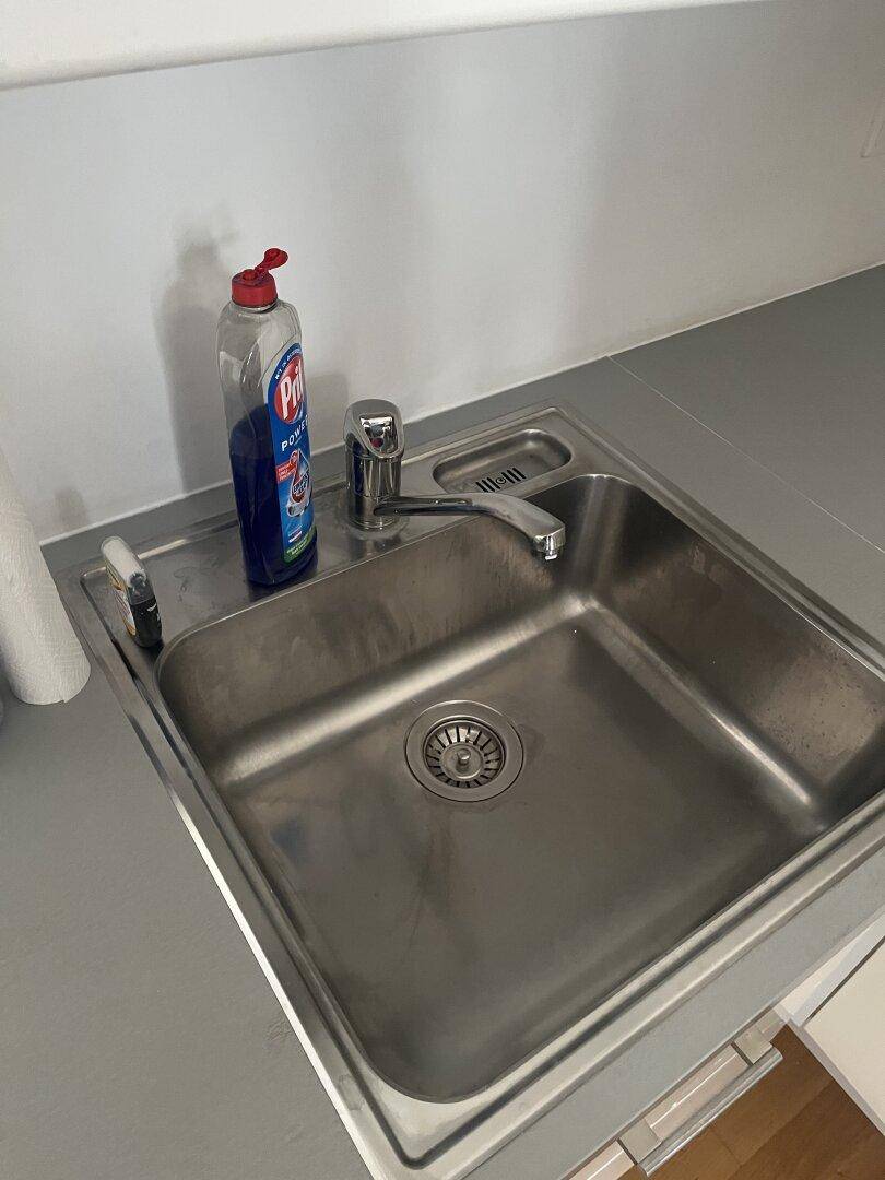 Detailansicht der Küchenspüle aus Edelstahl mit Armatur und Abtropffläche, sauber und bereit zur Nutzung.