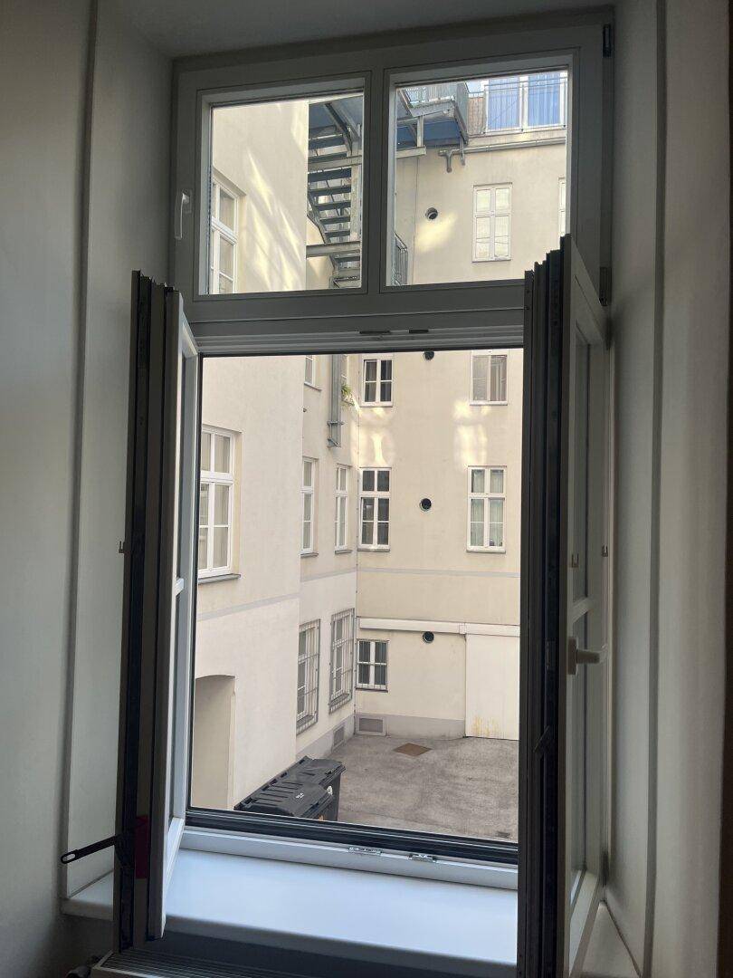 Fenster mit Blick auf den Innenhof, der viel Tageslicht in den Raum lässt.