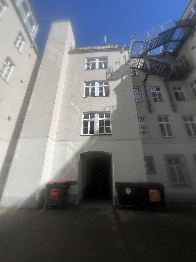 Innenhofansicht eines Altbaus mit mehreren Fenstern und einem Außentreppenhaus.