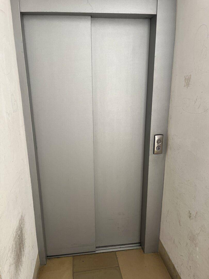 Moderner Aufzug mit silbernen Türen in einem Flur, bietet bequemen Zugang zu den Etagen.