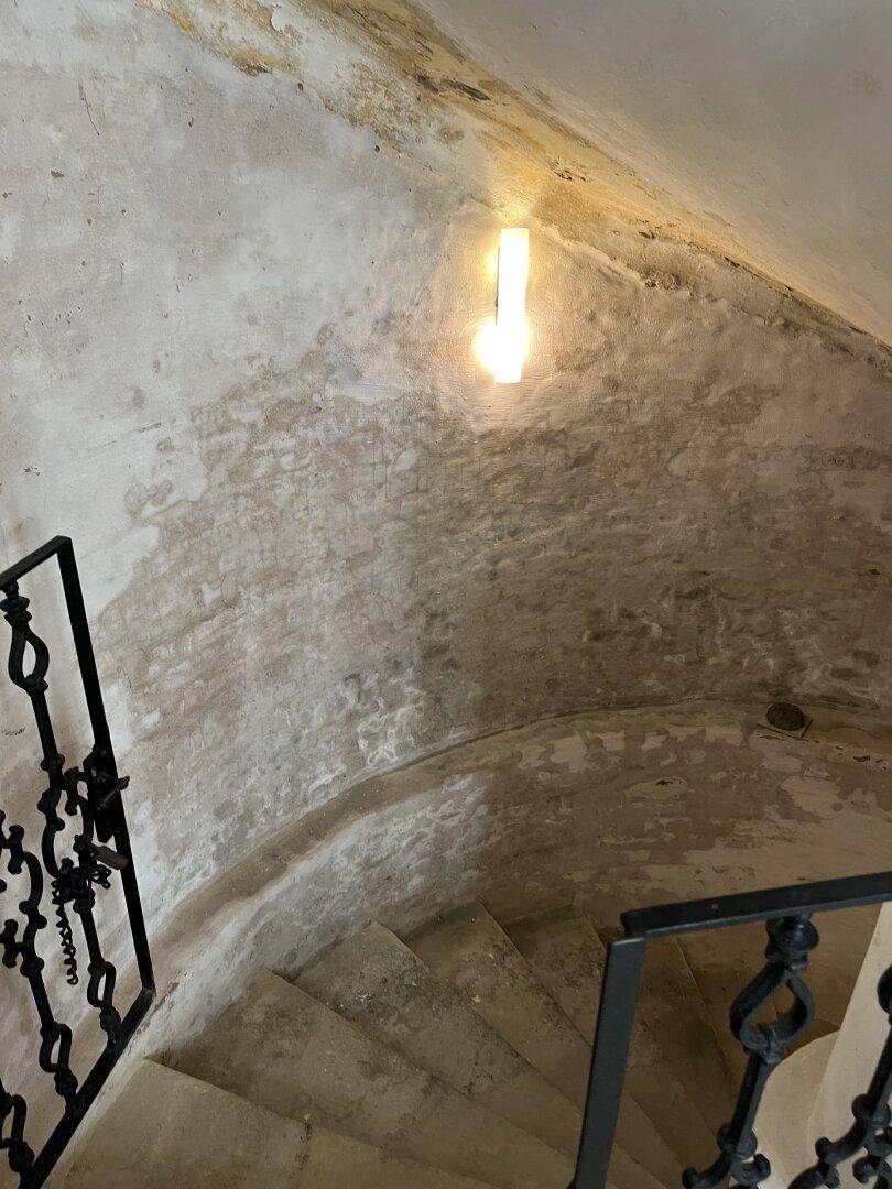 Historisches Treppenhaus mit schmiedeeisernem Geländer und abgenutzten Stufen, zeugt von Alter.