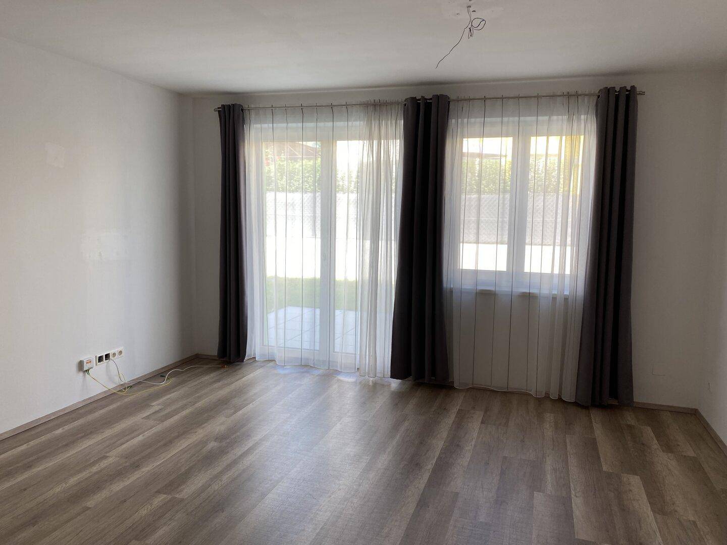 Geräumiges Wohnzimmer mit großen Fenstern und Zugang zum Garten oder zur Terrasse.