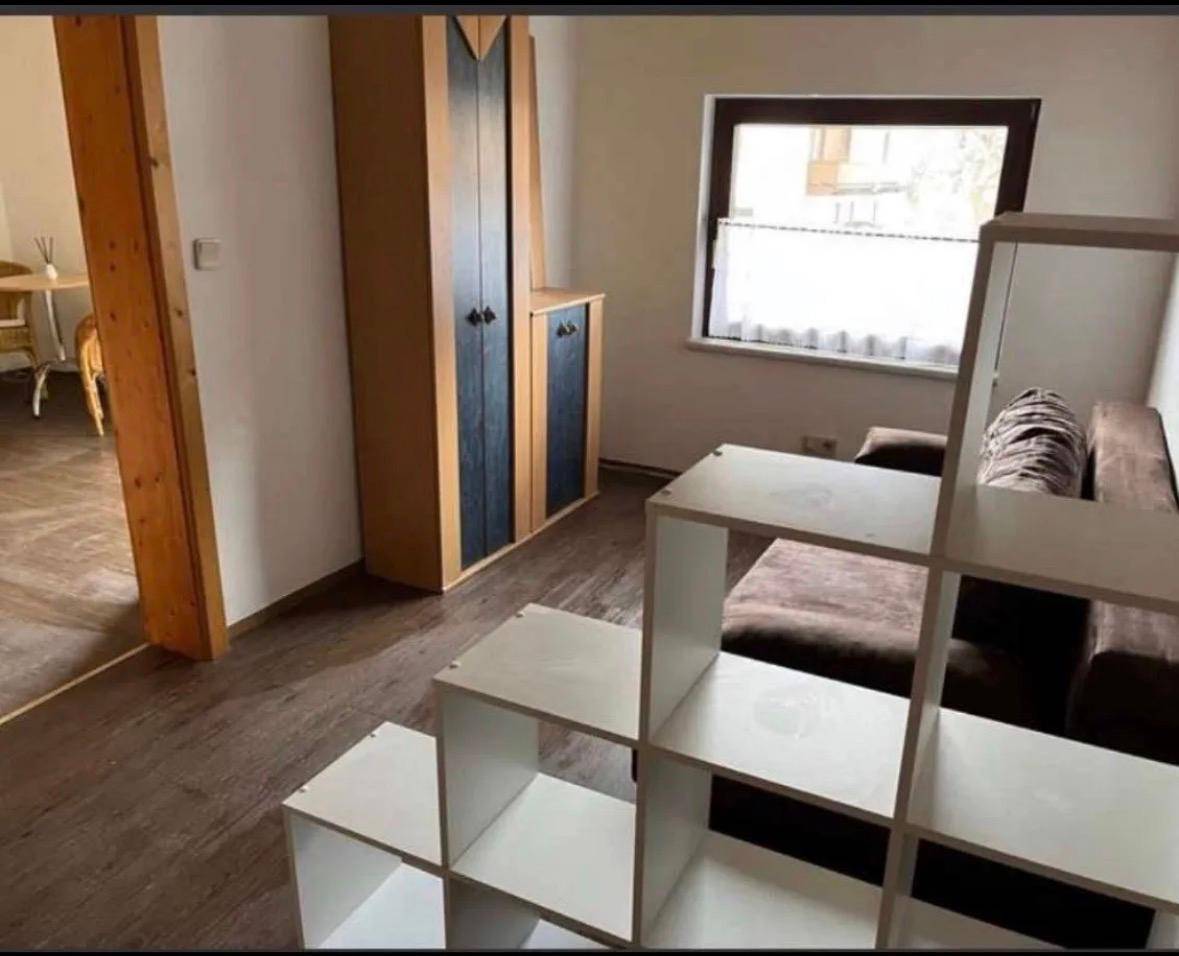 Wohnbereich mit Laminatboden, braunem Sofa und einem modularen weißen Regalsystem.