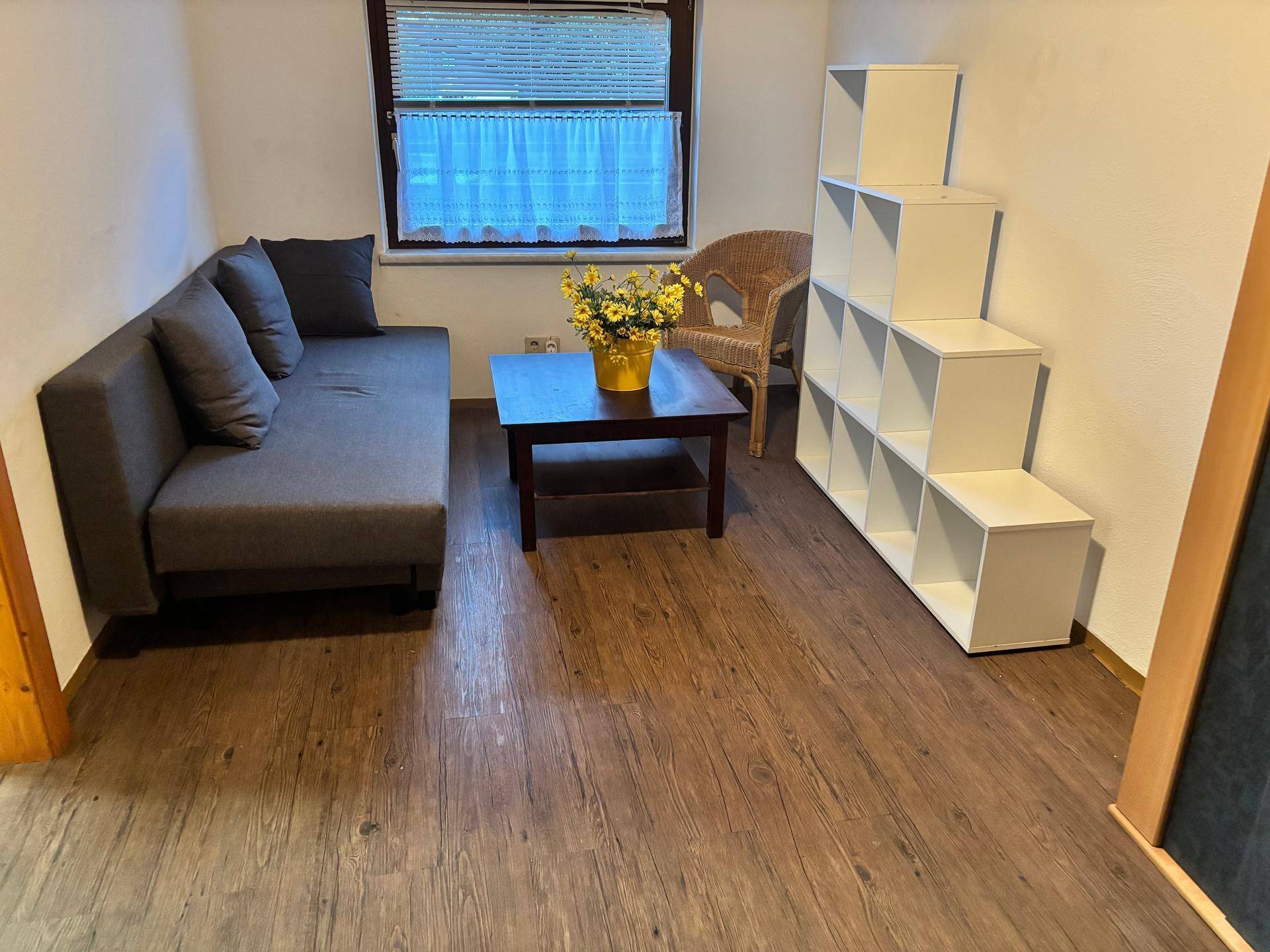 Gemütliches Wohnzimmer mit Sofa, Couchtisch und Stufenregal.