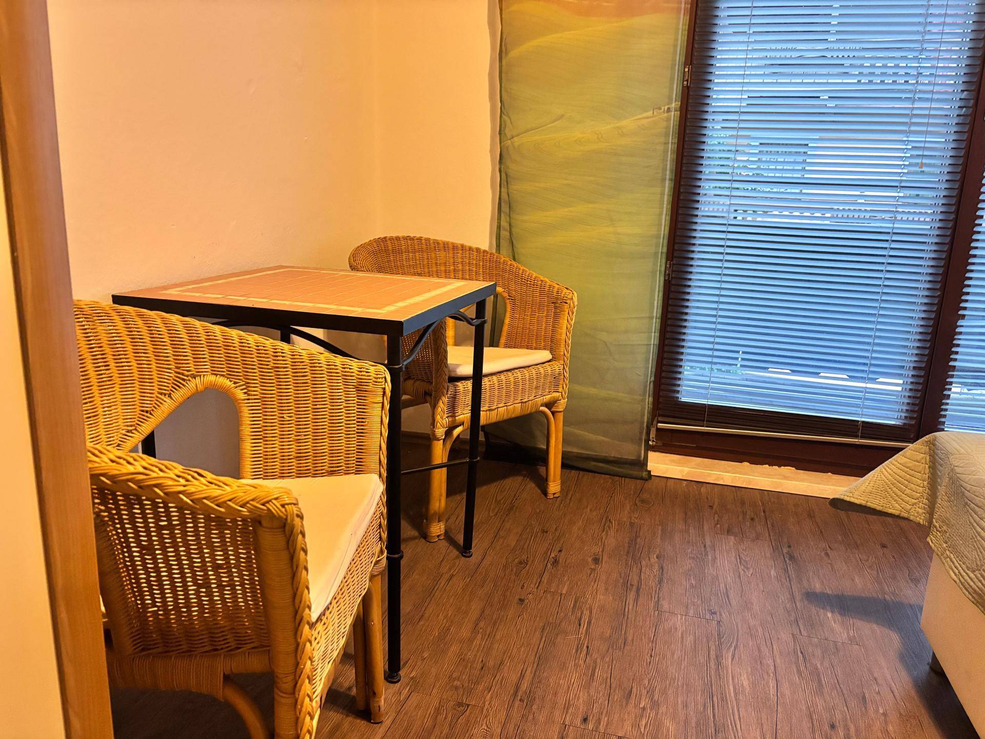 Kleine Sitzecke mit Korbstühlen und Tisch neben dem Fenster im Schlafzimmer.