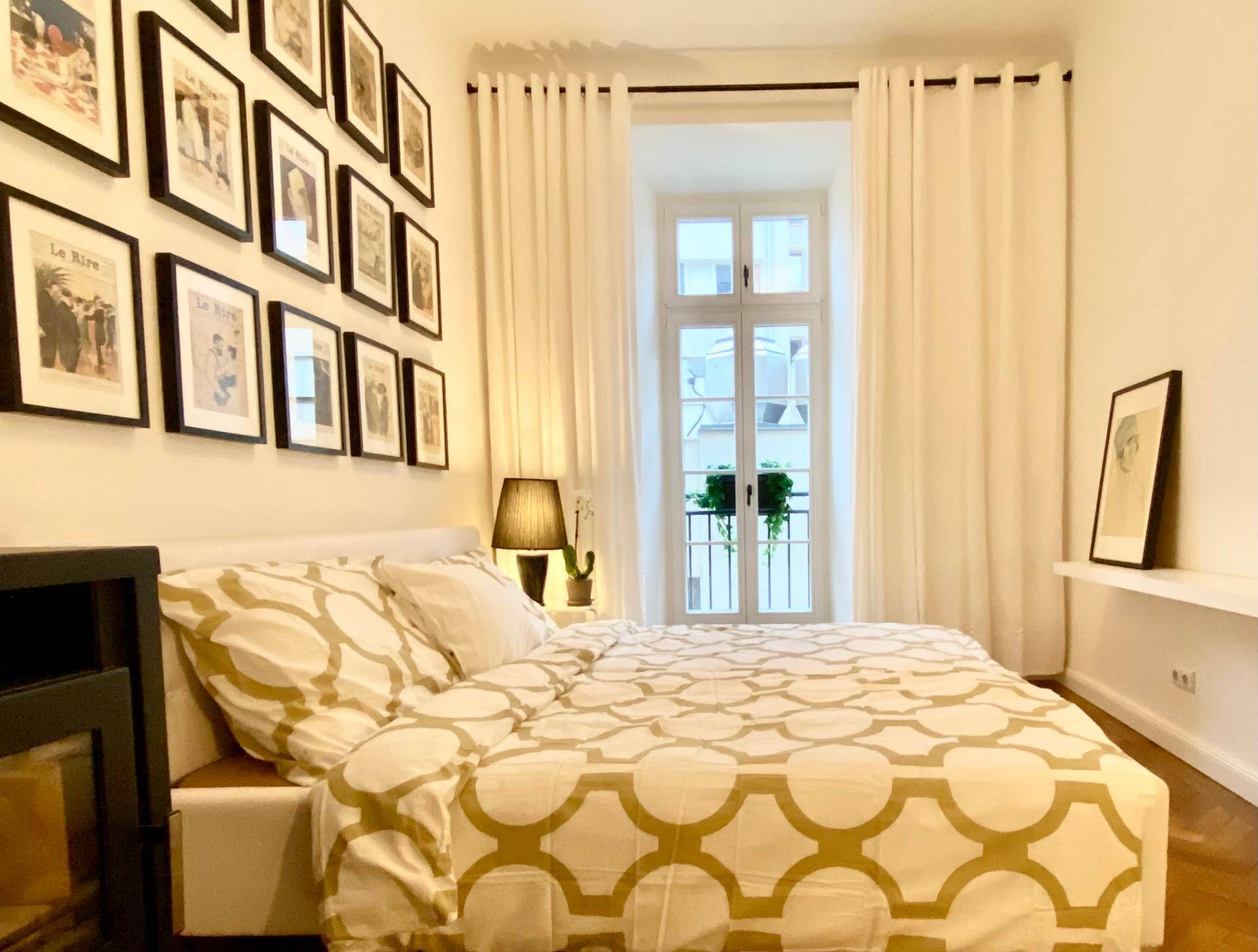 Schlafzimmer mit Doppelbett, gemusterter Bettwäsche und Zugang zu einem französischen Balkon.