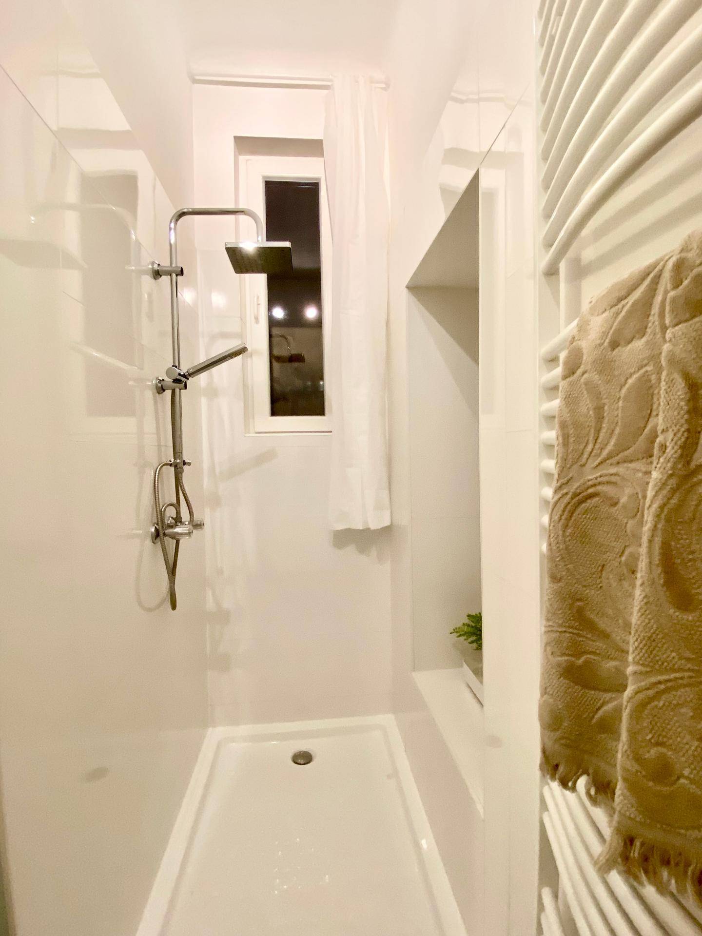 Modernes Badezimmer mit Duschkabine, weißer Fliesenwand und Handtuchheizkörper.