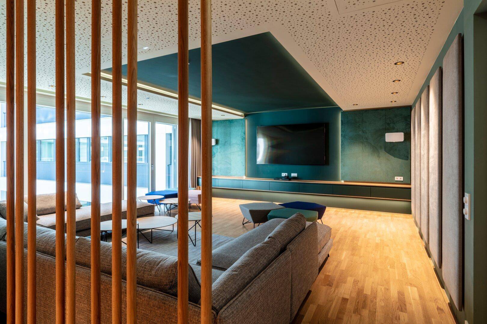 Gemütlicher Medienraum mit großem Sofa, Fernseher und akustischen Wandpaneelen für entspannte Abende.