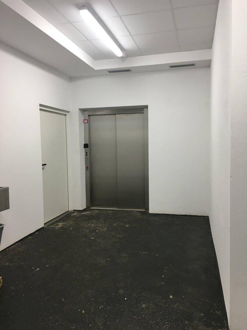 Heller Flur mit einem modernen Aufzug und weiß gestrichenen Wänden, bereit für die Nutzung.