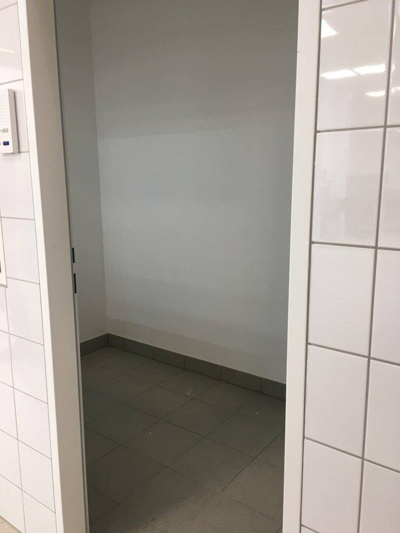 Kleiner, leerer Raum mit hellgrauen Fliesen und weiß gestrichenen Wänden, ideal als Abstellraum.