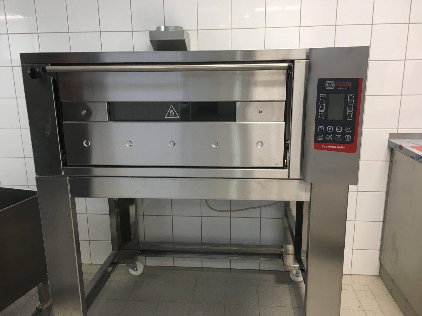 Großer professioneller Edelstahlofen mit digitaler Steuerung in einer gefliesten Gewerbeküche.