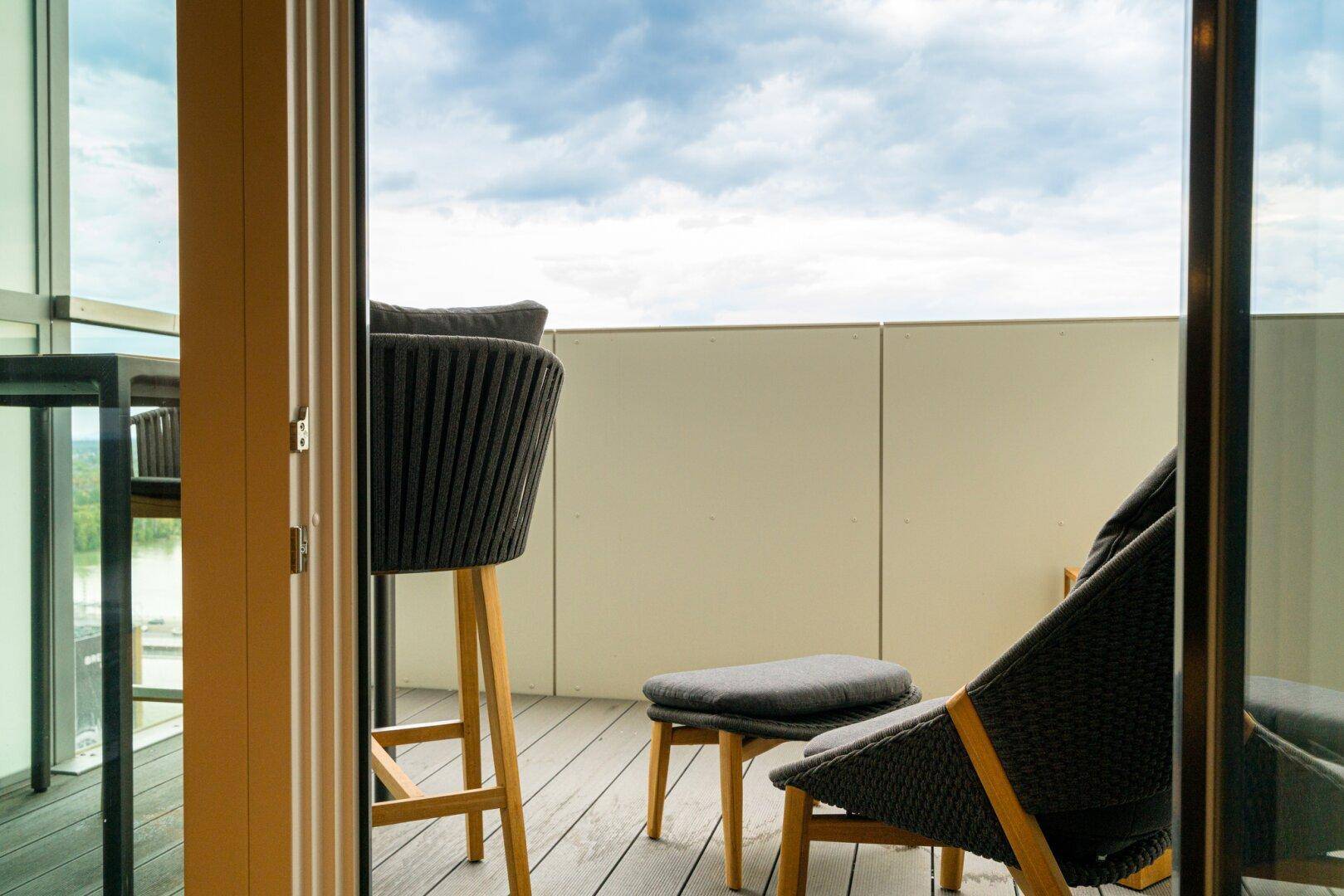Gemütlicher Balkon mit modernen Outdoor-Möbeln und weitem Blick in den Himmel.