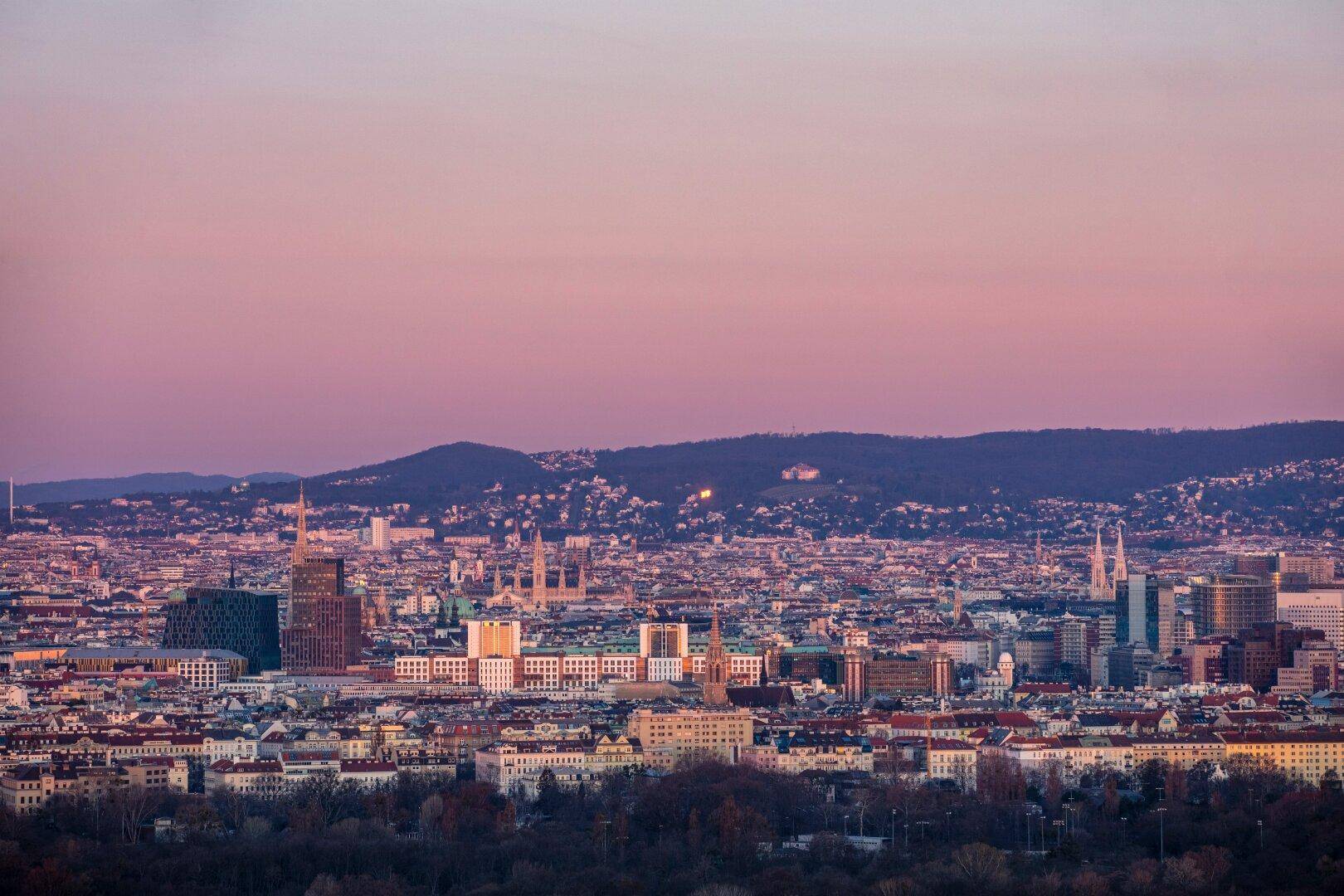 Panoramablick über die Stadt bei Sonnenuntergang mit Bergen im Hintergrund.