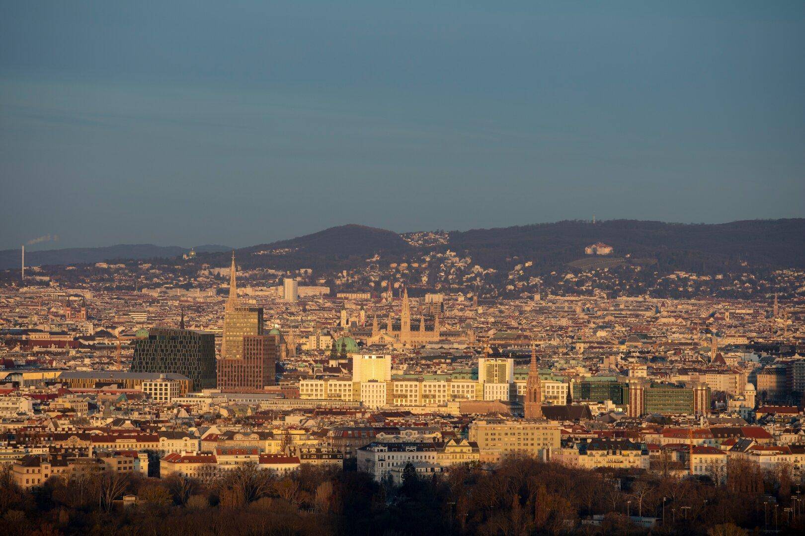Panoramablick über die Stadt mit vielen Gebäuden und grünen Hügeln im Hintergrund bei Tageslicht.