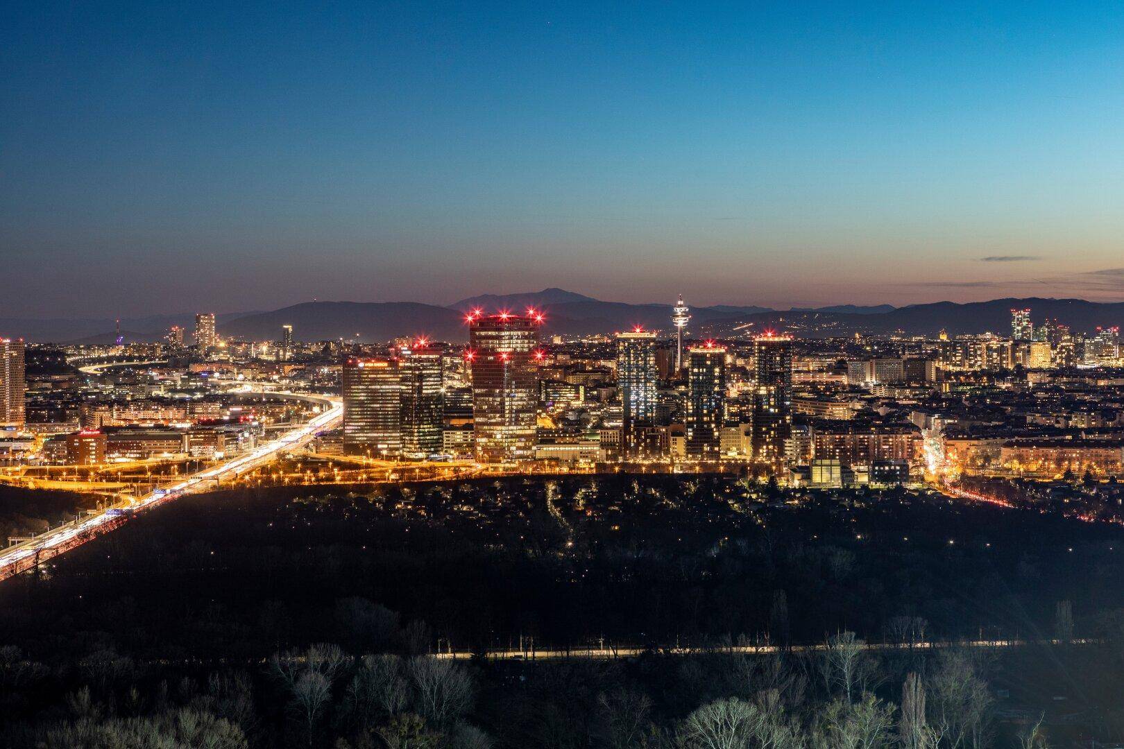 Beeindruckender Nachtblick auf die beleuchtete Stadt mit Hochhäusern und Autobahnen.