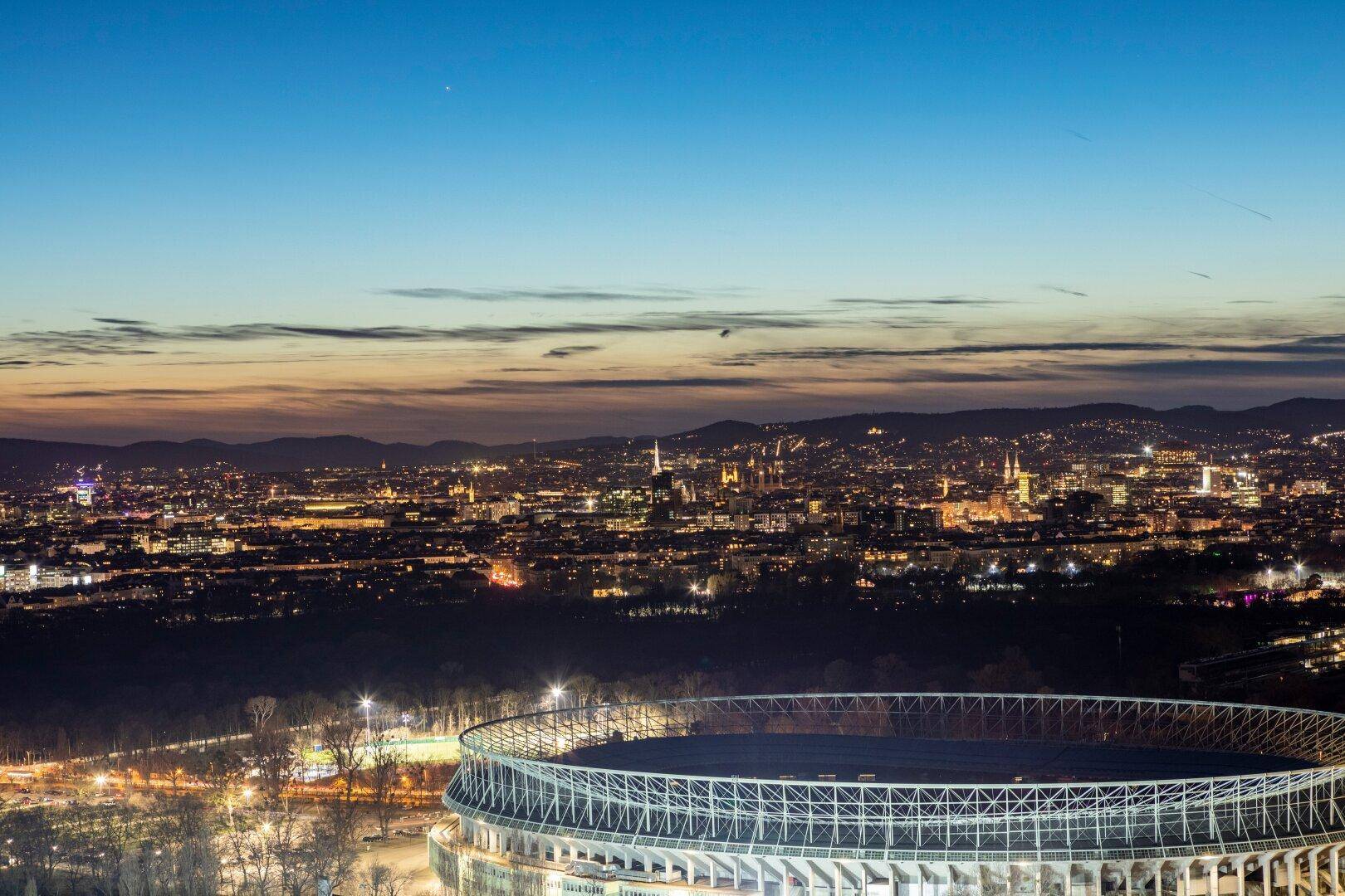 Nächtlicher Panoramablick auf die beleuchtete Stadt und ein Stadion.