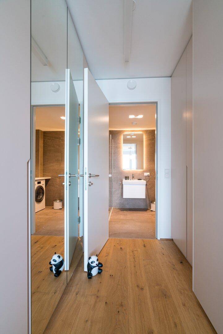 Heller Flur mit Spiegelschränken und Zugang zu einem modernen Badezimmer.