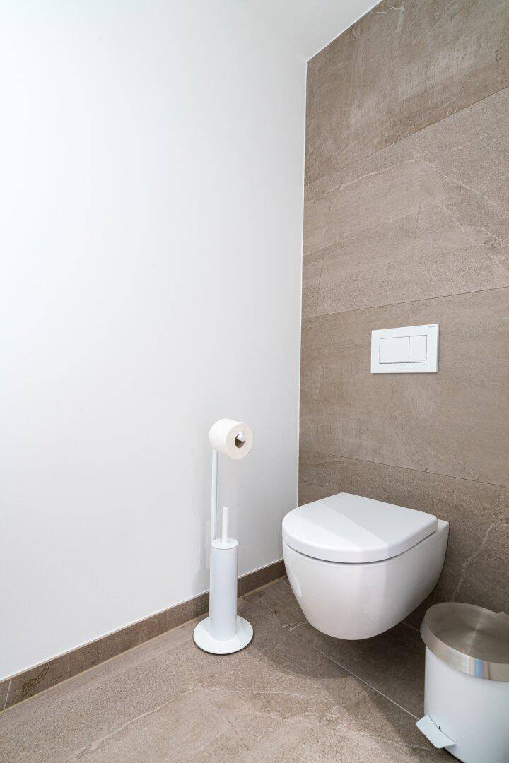 Separates WC mit wandhängender Toilette und modernen Fliesen an der Wand.
