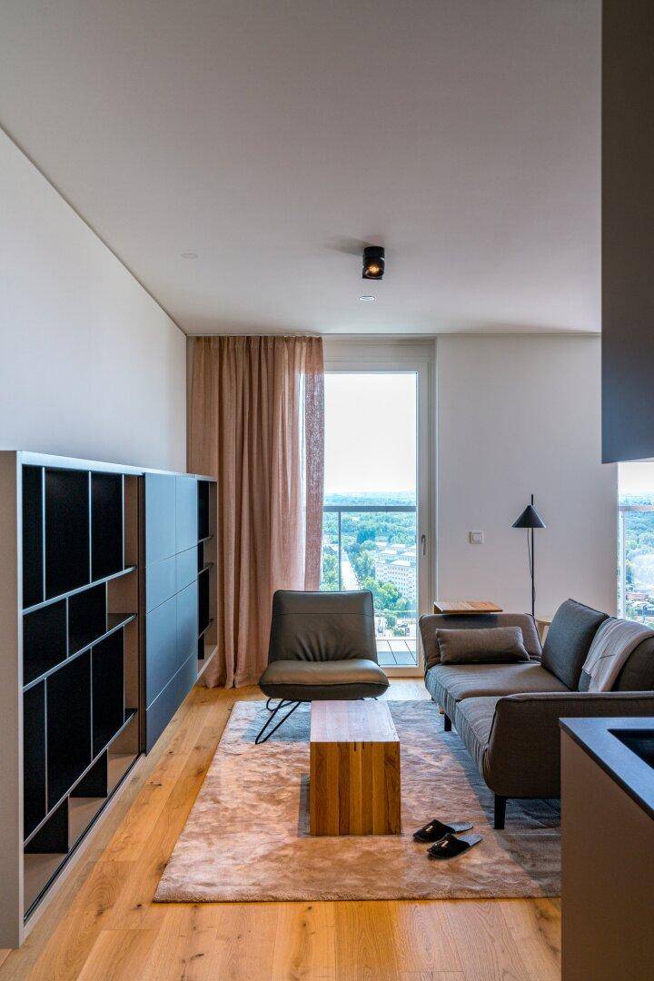 Gemütliches Wohnzimmer mit bequemer Couch, Holzboden und großen Fenstern mit Weitblick.