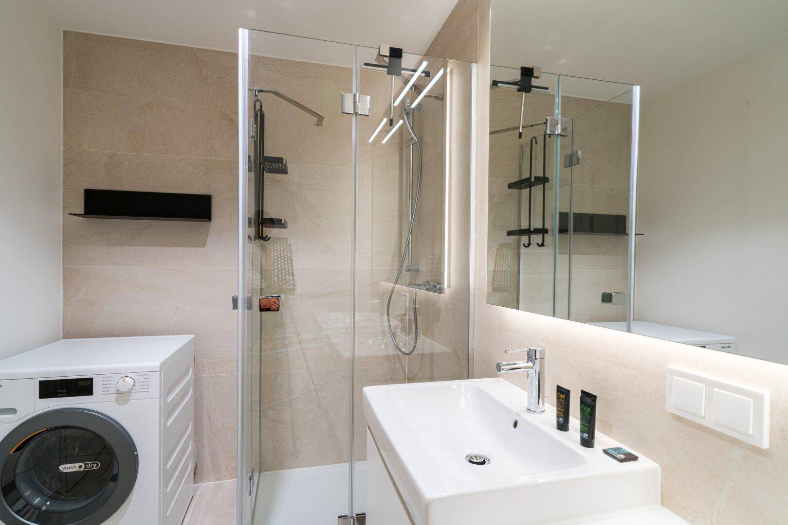 Modernes Badezimmer mit Duschkabine, Waschbecken und Waschmaschine.