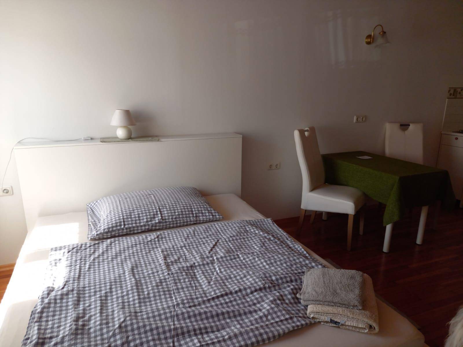 Gemütliches Schlafzimmer mit Einzelbett und karierter Bettwäsche, ergänzt durch einen kleinen Essbereich.