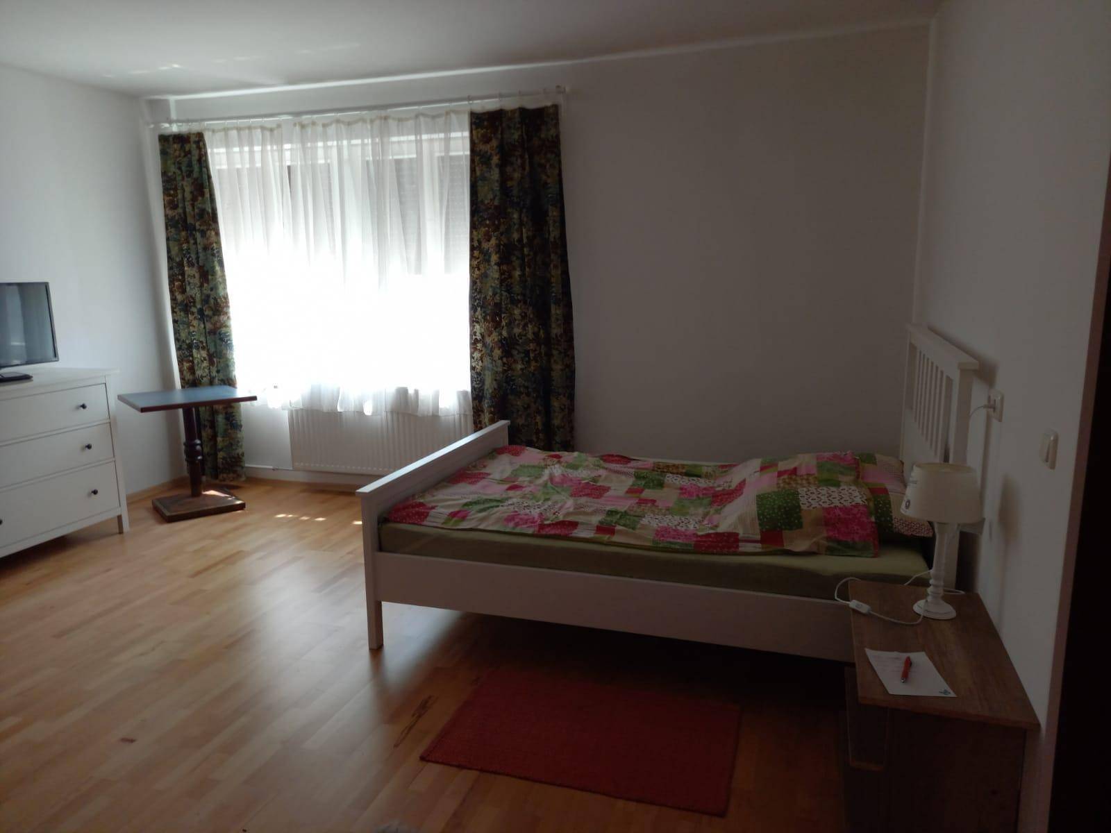Geräumiges Schlafzimmer mit Bett, Kommode und Fernseher, mit Blick auf die Umgebung.