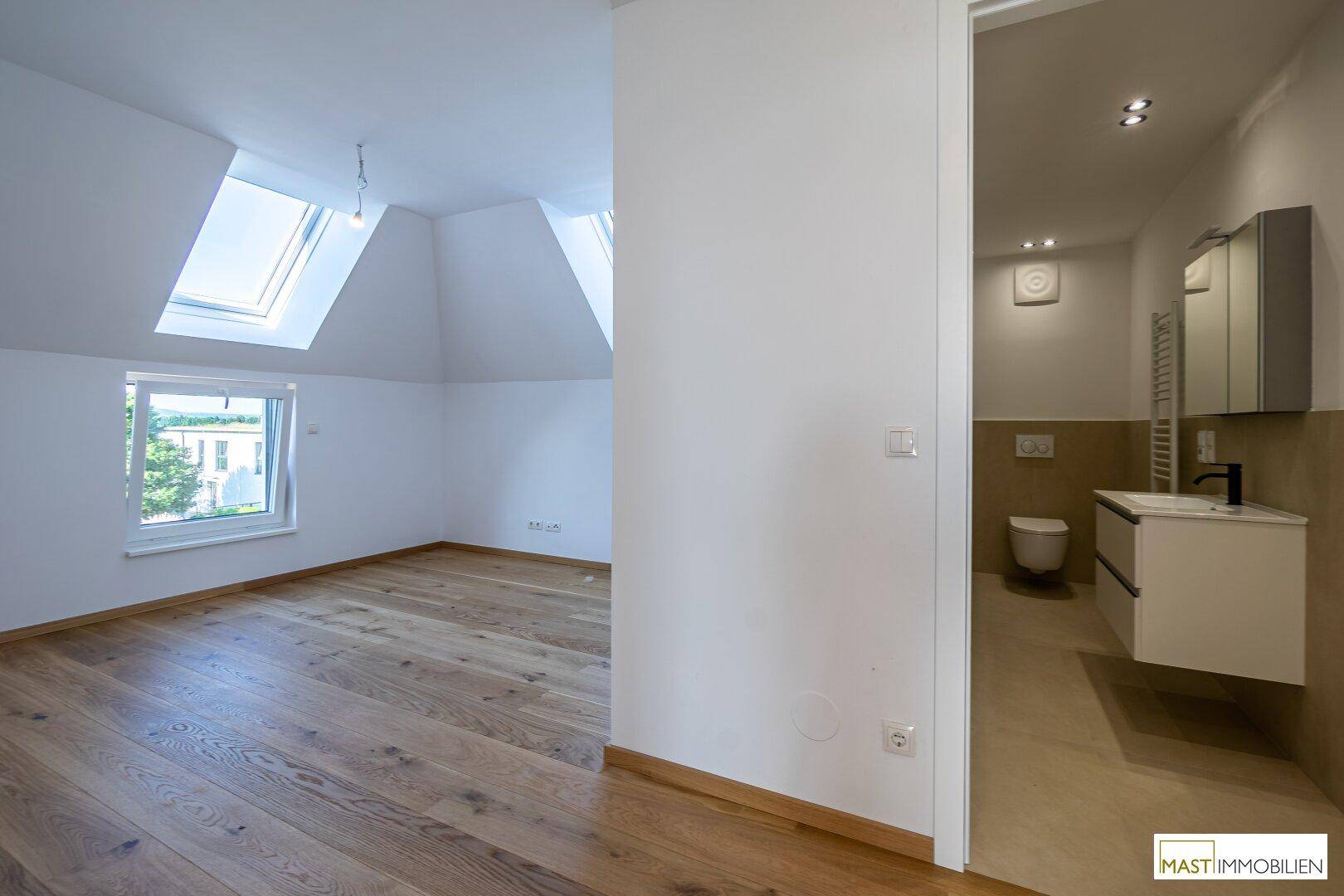 Übergangsbereich mit Holzboden, der zu einem hellen Zimmer und einem modernen Badezimmer führt.