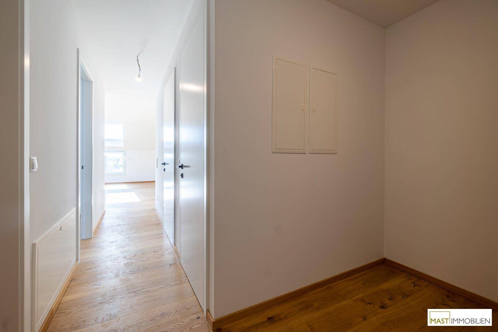 Heller Flur mit Holzboden und weißen Türen, der verschiedene Räume miteinander verbindet.