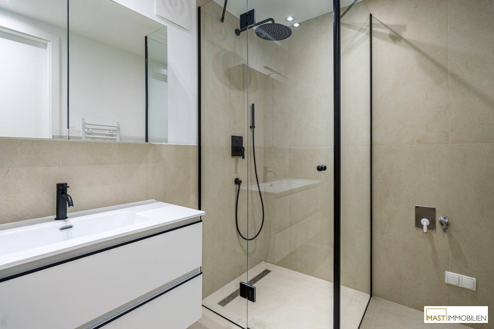 Modernes Badezimmer mit begehbarer Dusche, schwarzen Armaturen und beigefarbenen Fliesen.