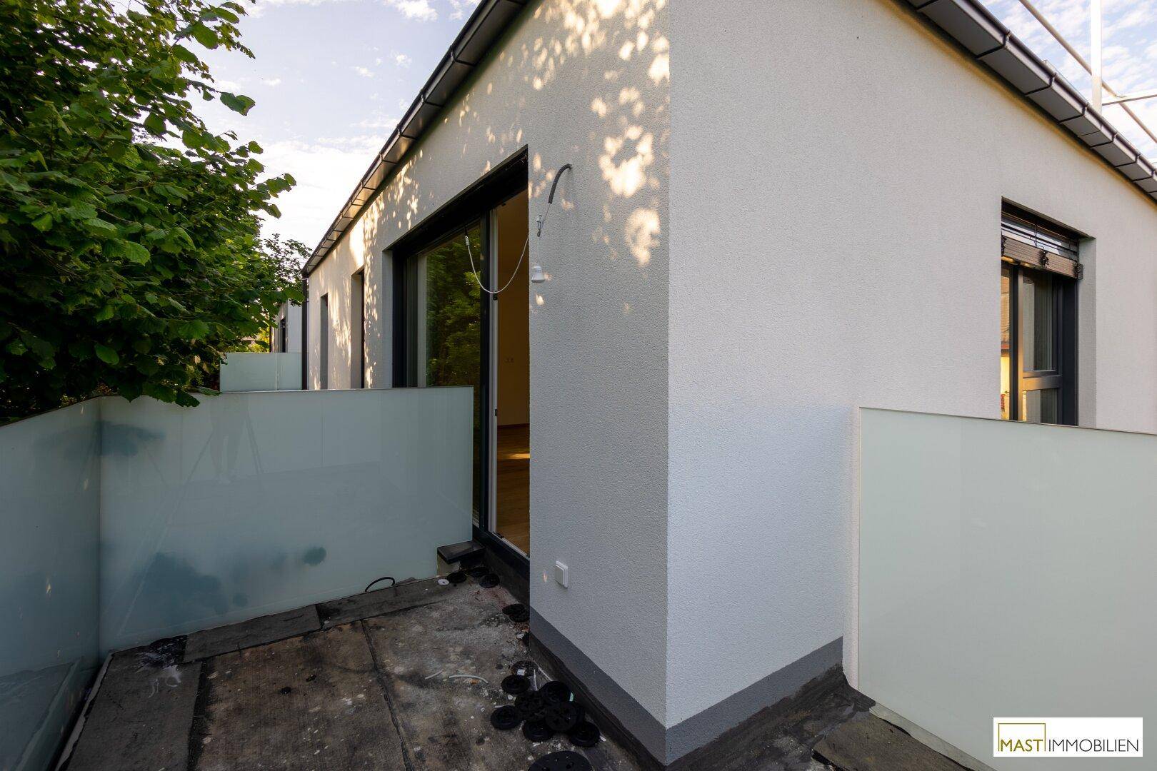 Kleine Terrasse mit Glasbrüstung und Blick ins Grüne, ideal für entspannte Stunden im Freien.