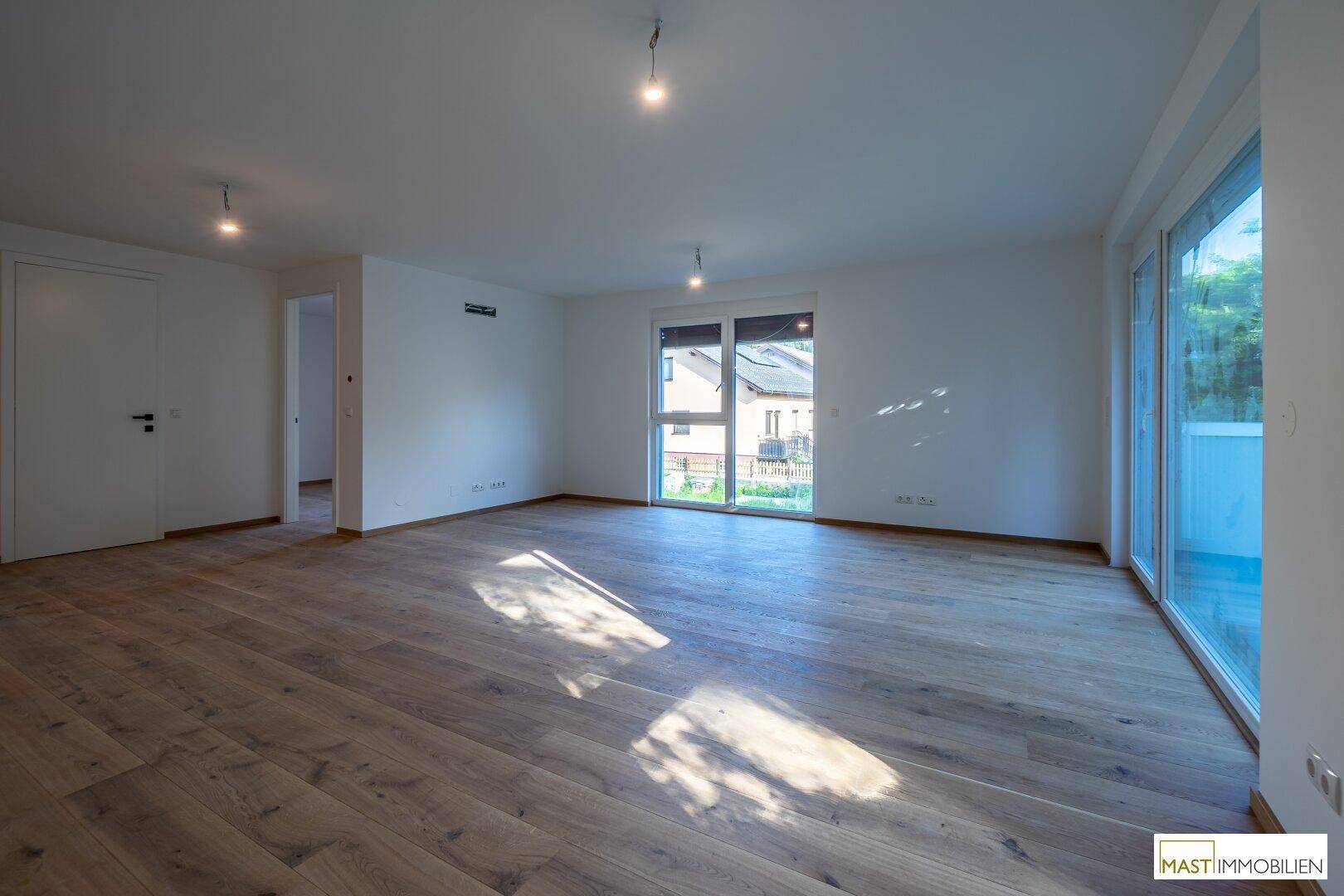 Heller Wohnbereich mit Holzboden und Blick auf die Nachbarschaft, bietet viel Tageslicht.