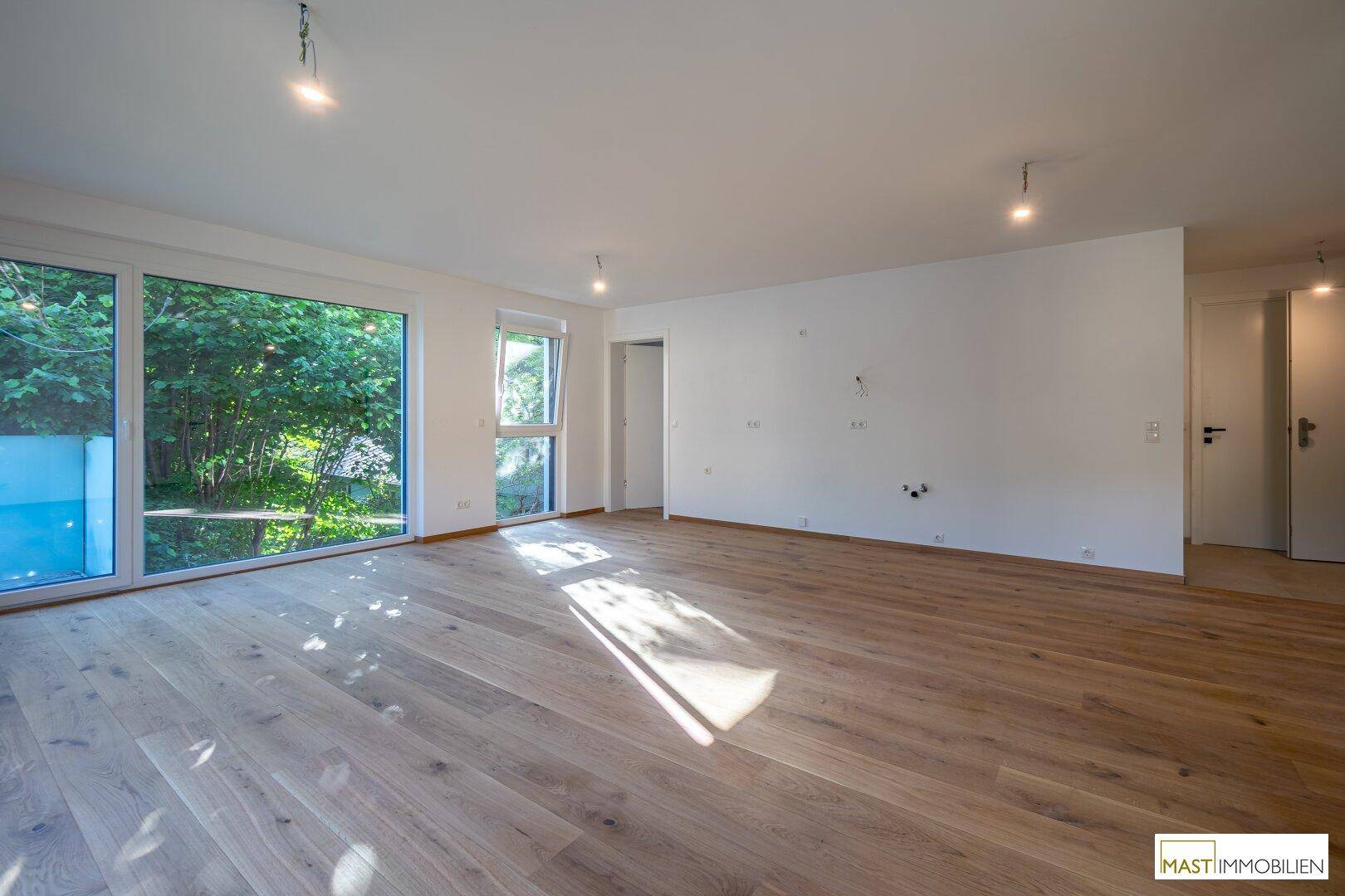 Lichtdurchfluteter Wohnbereich mit modernem Holzboden und Zugang zu den Außenbereichen, sehr einladend.