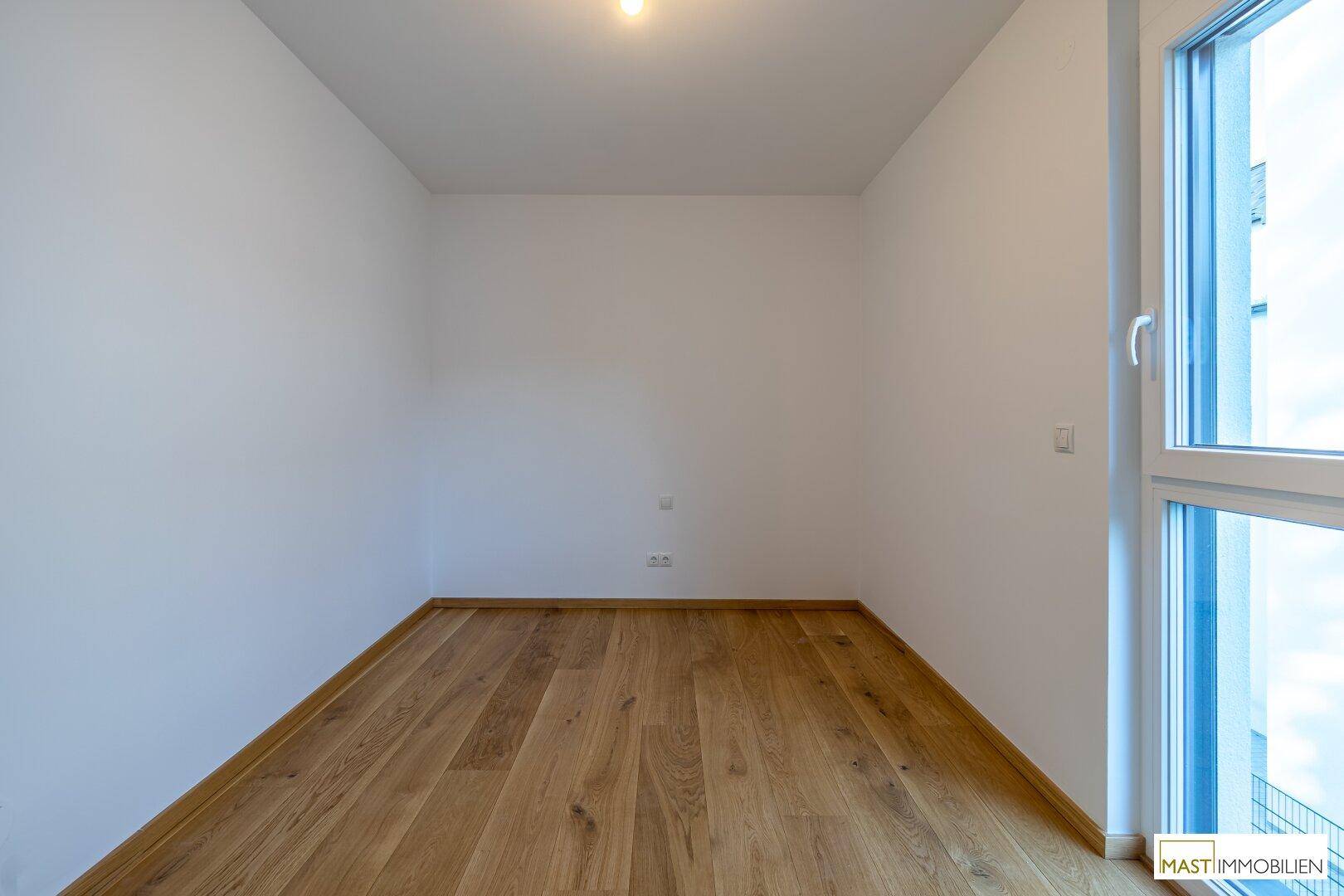 Kompaktes Zimmer mit Holzboden und Fenster, bietet eine ruhige Atmosphäre.