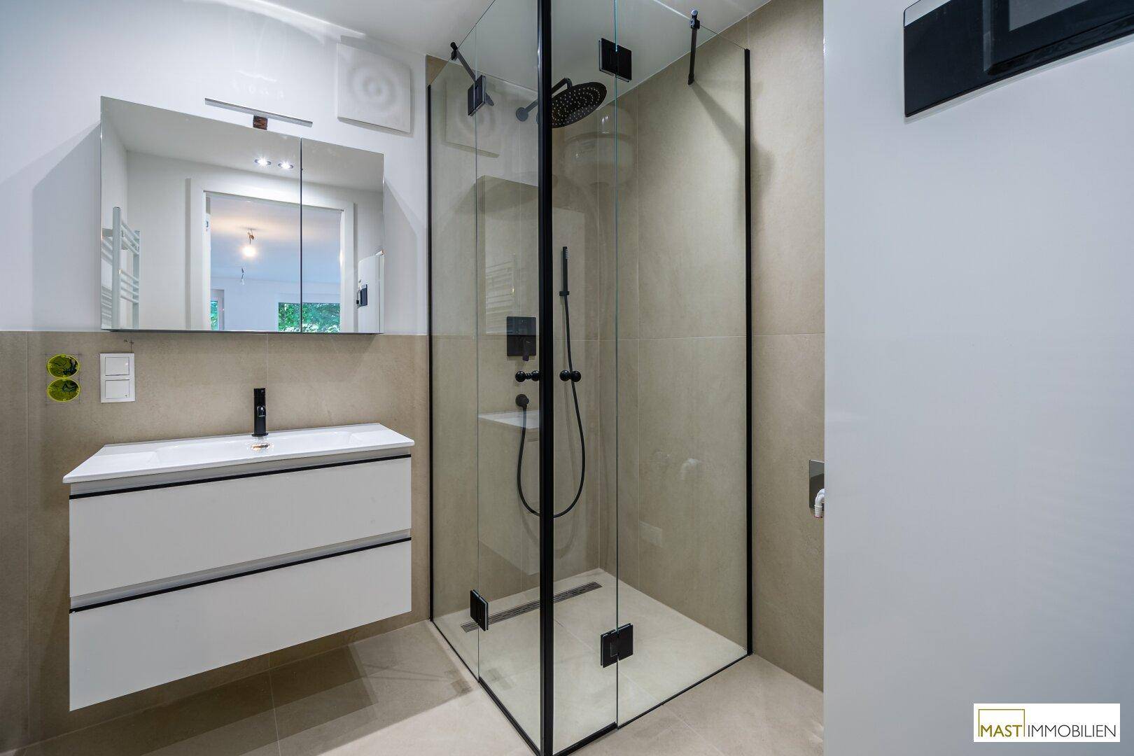 Modernes Badezimmer mit begehbarer Dusche, eleganten Fliesen und schwebendem Waschtisch.