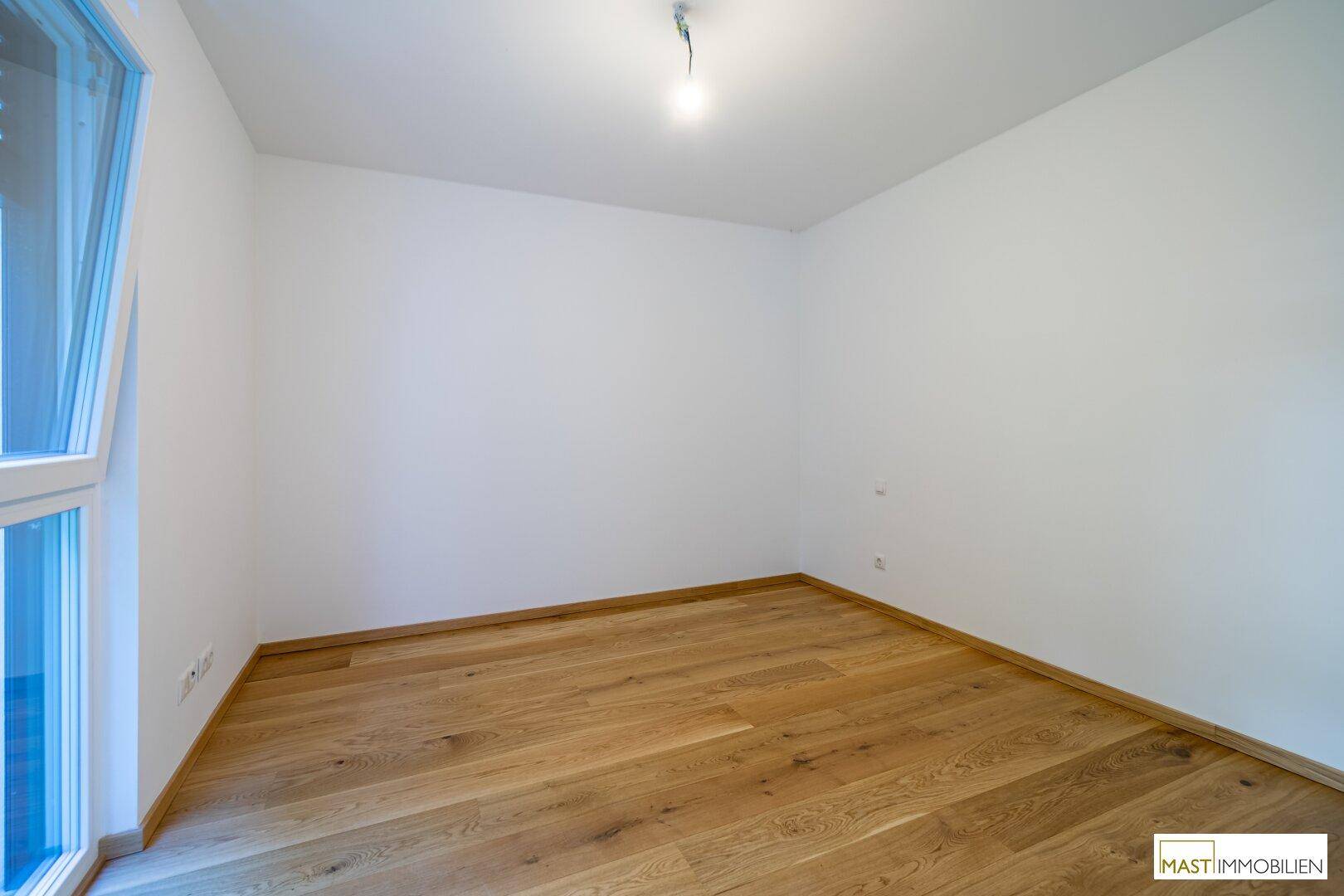 Ruhiges Zimmer mit Parkettboden und viel Tageslicht, perfekt für ein Schlafzimmer oder Büro.