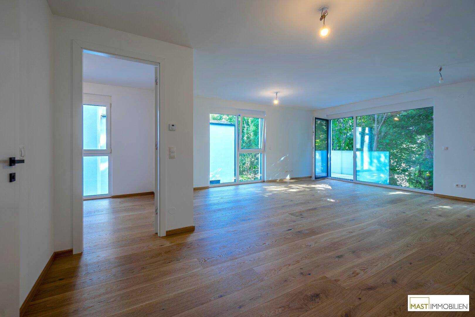 Heller Wohnbereich mit Parkettboden und Zugang zu einem Balkon, der viel Licht bietet.