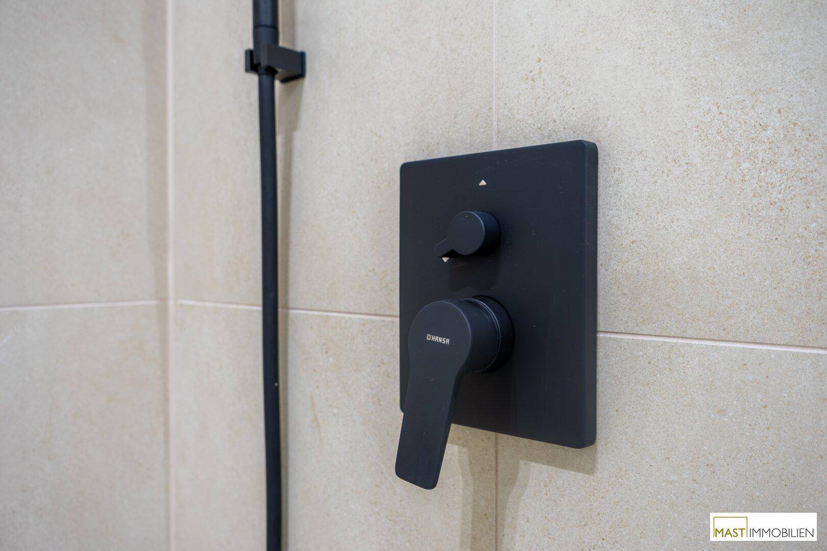 Detailaufnahme der modernen schwarzen Armatur in der Dusche, passend zum zeitgenössischen Design.