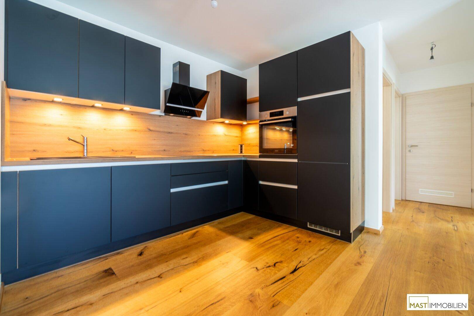 Detailansicht der modernen Einbauküche mit dunklen Fronten, integrierten Geräten und Holz-Arbeitsplatte.
