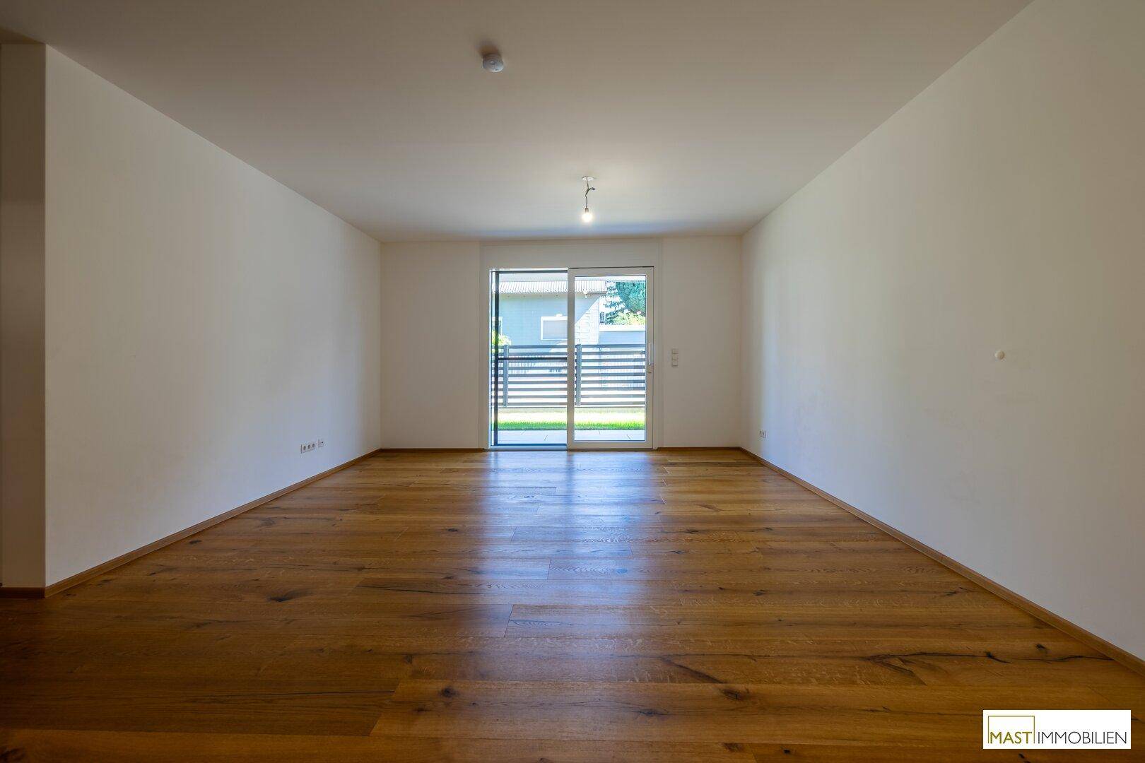 Geräumiges Wohnzimmer mit großen Schiebetüren, die Zugang zum Garten und viel natürliches Licht bieten.