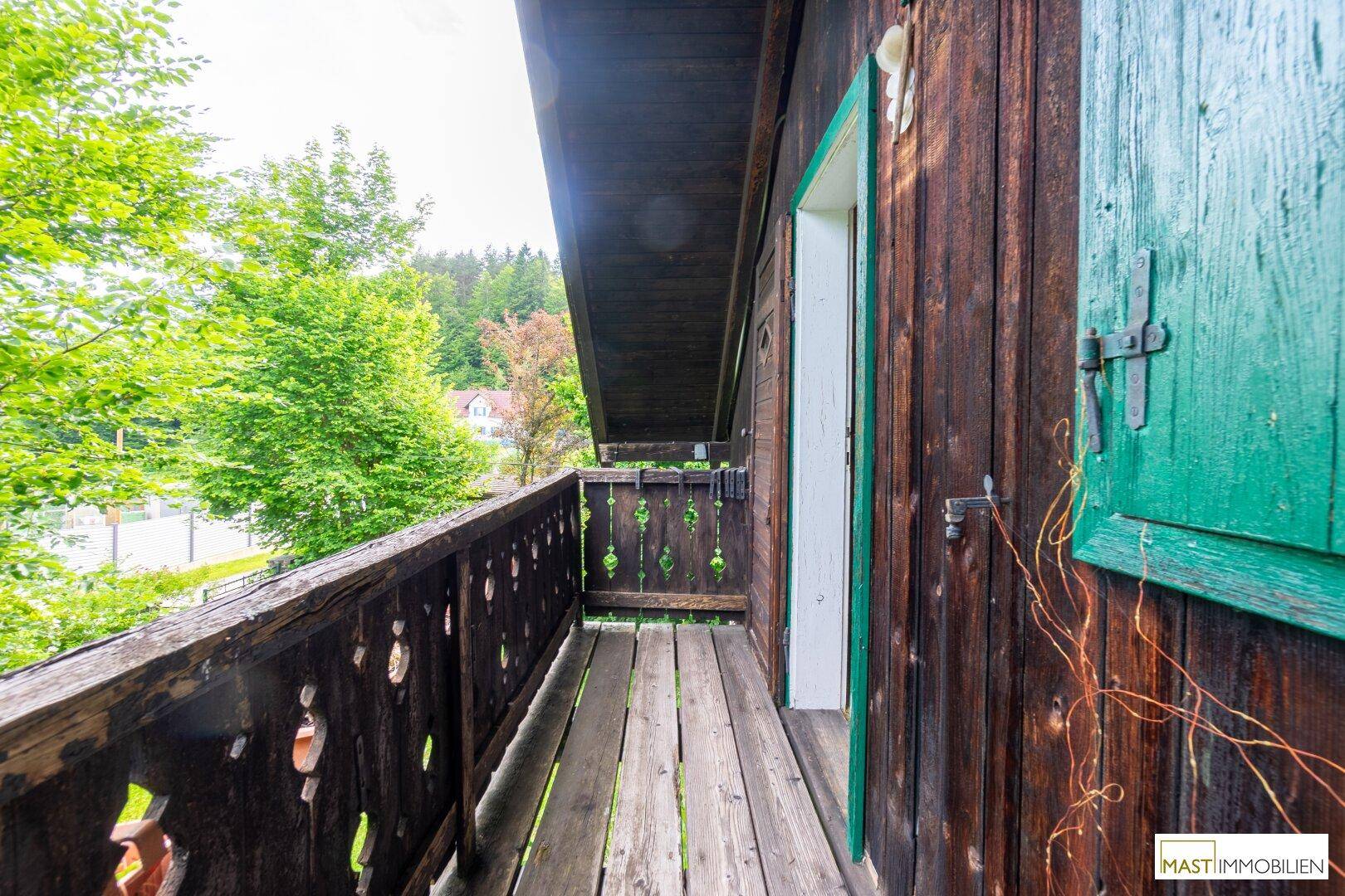 Traditioneller Holzbalkon mit Blick auf die grüne Umgebung und die Straße.
