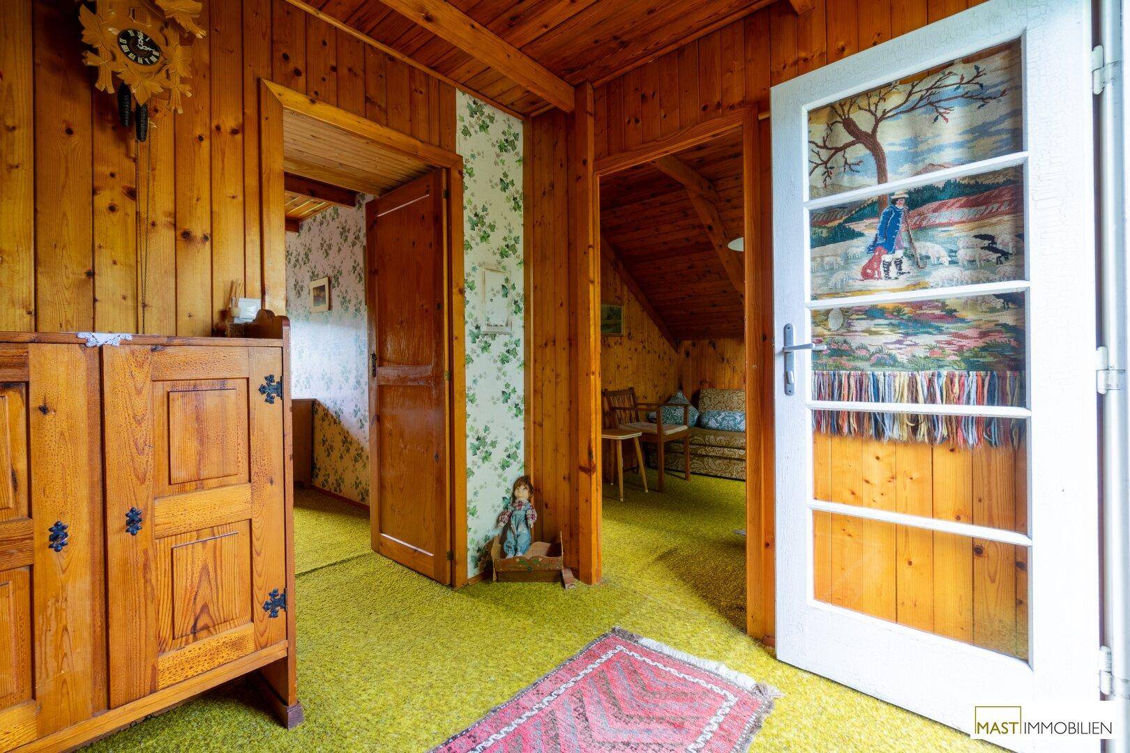 Rustikaler Flur mit Holzvertäfelung, Teppichboden und Zugang zu weiteren Zimmern im Dachgeschoss.