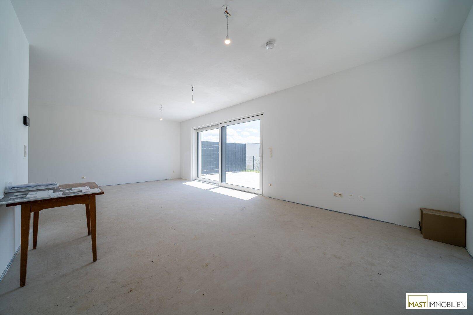 Heller, offener Wohnbereich mit großen Fenstern und direktem Zugang zur sonnigen Terrasse.