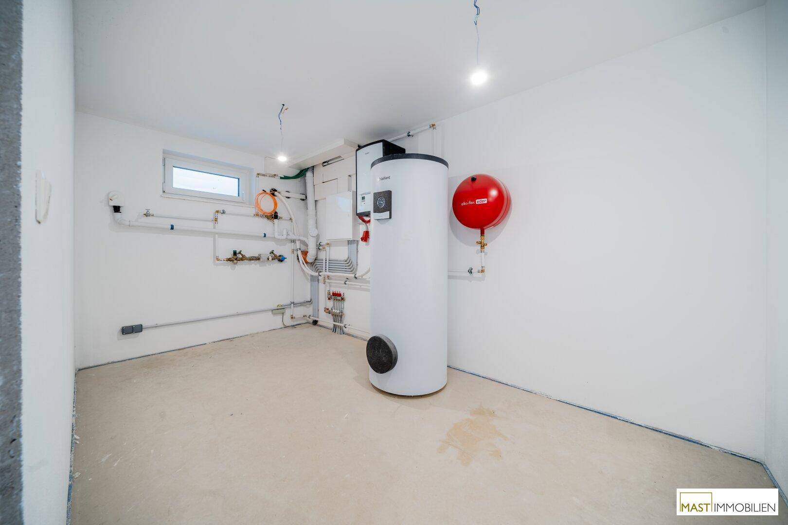 Technikraum mit Warmwasserspeicher und Heizungsinstallationen, bereit für den Anschluss.