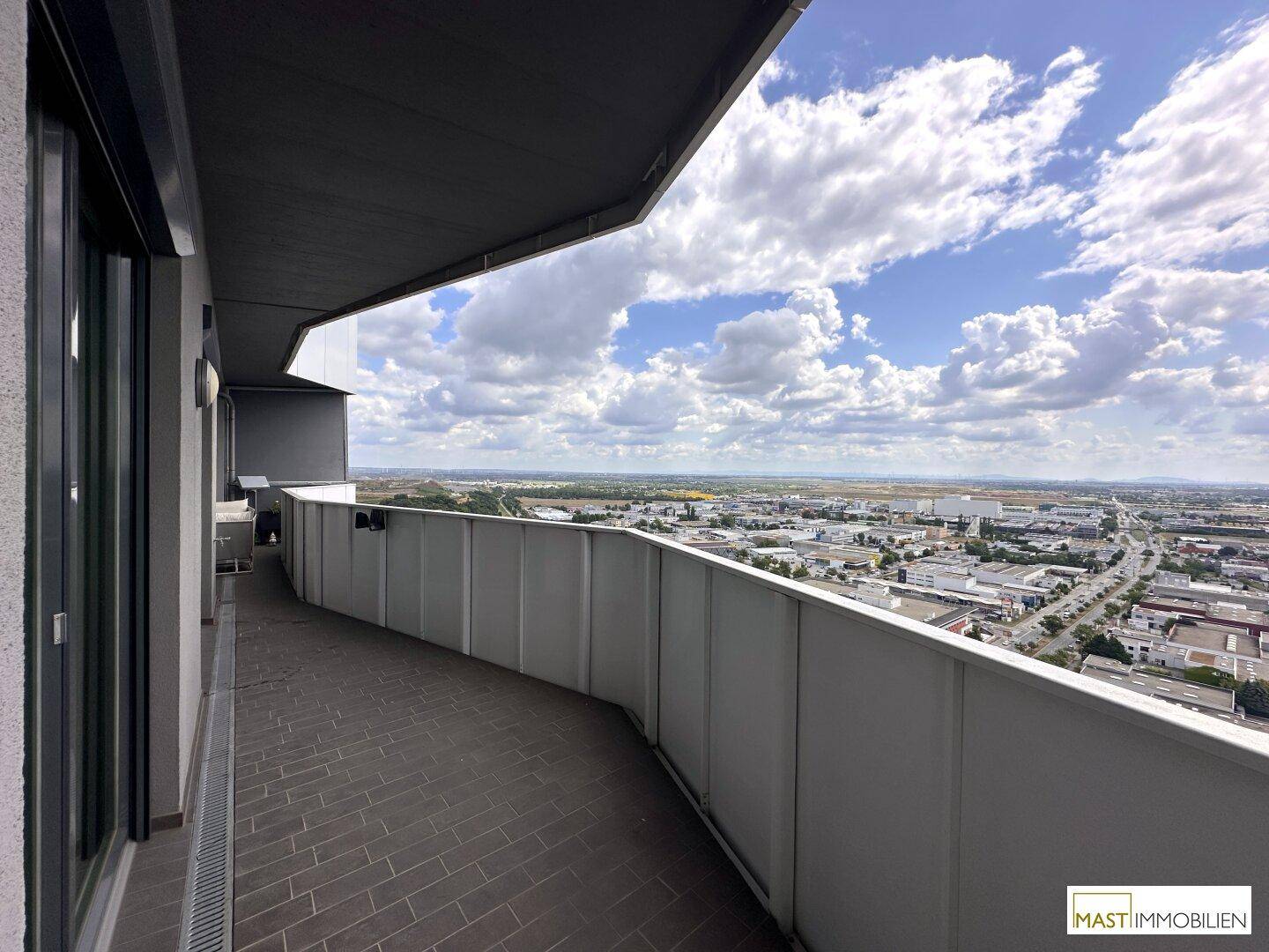 Langer, schmaler Balkon mit Fliesenboden und einem weiten Panoramablick über die Stadt.