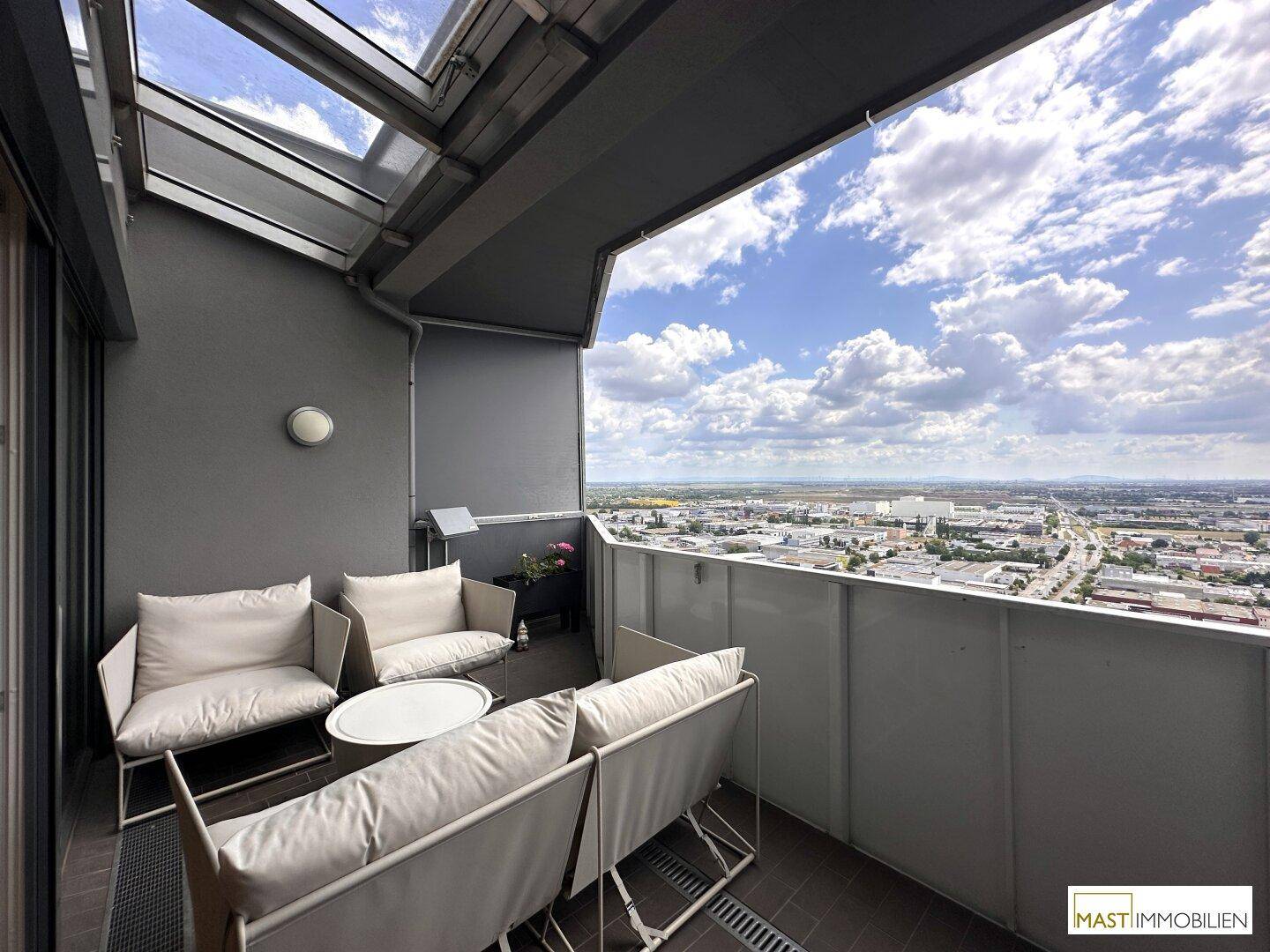 Möblierter Balkon mit bequemen Sitzgelegenheiten und einem weiten Panoramablick über die Stadtlandschaft.